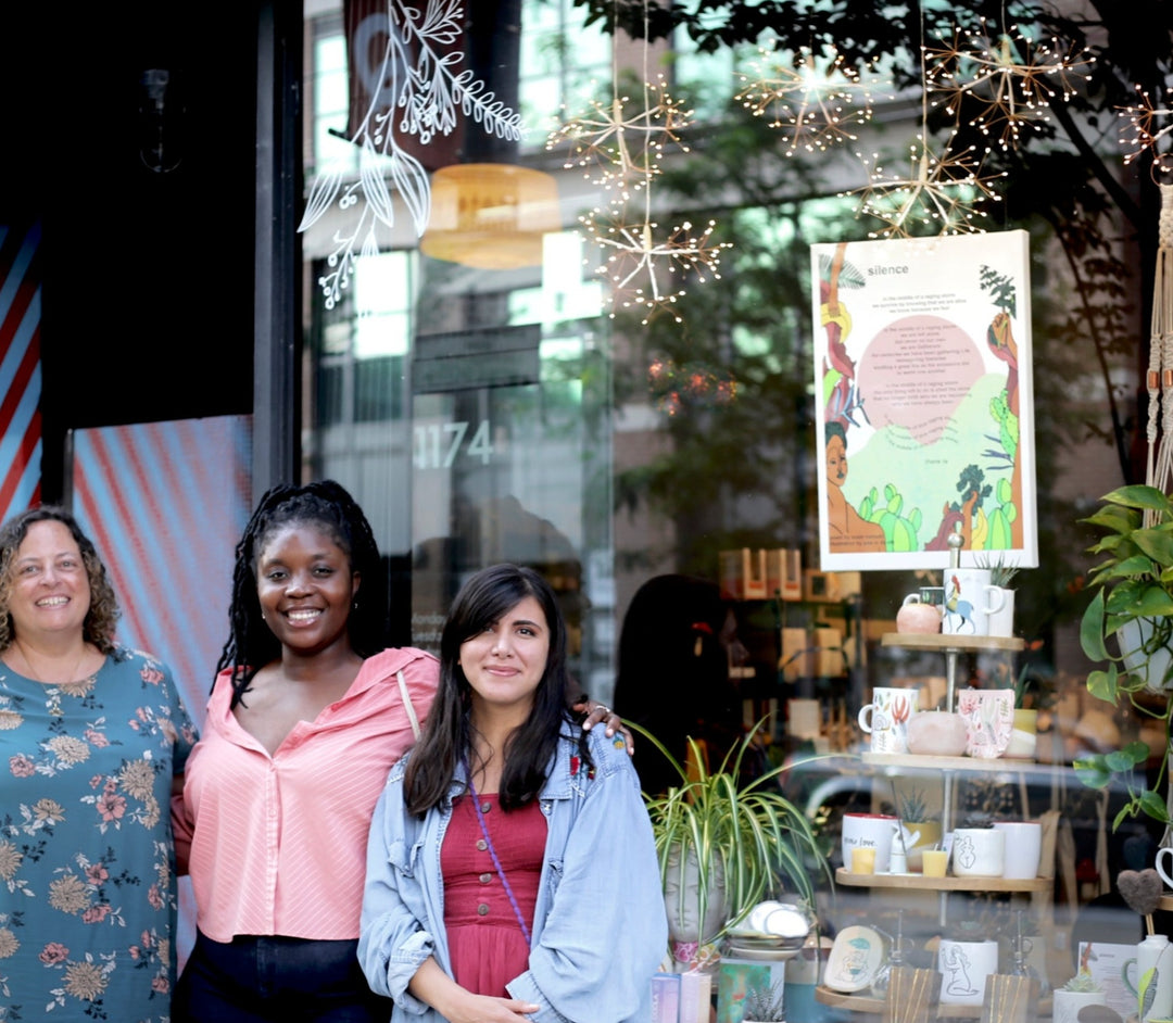 Helen + Hildegard Founder, Sonya D'Cunha (left), smiling with "Silence Poem" artists, Susie Mensah (centre) and Jess De Vitt (right) outside the Helen+Hildegard window with the SILENCE Canvas on display behind the window pane.